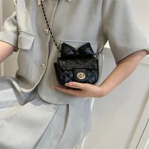 Detail of black quilted crossbody bag with golden twist lock and elegant bow