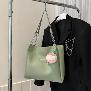 Detail of green tote bag with metal chain strap and cute peach plush charm detail