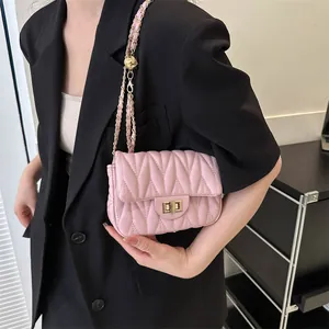 Pink quilted crossbody bag with gold chain strap shown on model in black blazer