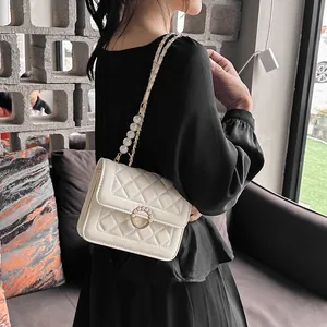 Close-up of quilted cream crossbody bag featuring oversized pearls on the shoulder strap