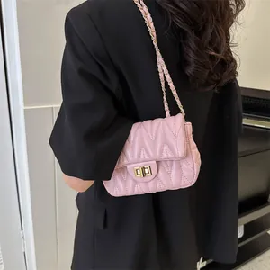 Detail of pink matelassé crossbody bag featuring gold twist lock and chain strap