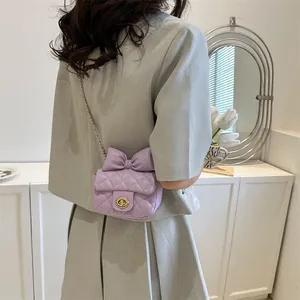 Detail of light purple quilted mini bag featuring a large bow and gold rotary lock buckle