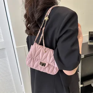 Detail of pink quilted shoulder bag with gold chain strap and wave texture finish