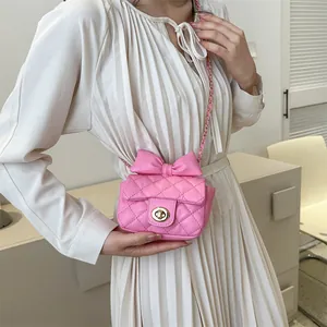 Close-up of pink quilted crossbody bag with decorative bow and golden chain strap
