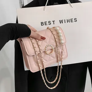 Detailed view of the pink quilted crossbody bag featuring a large pearl chain and gold buckle