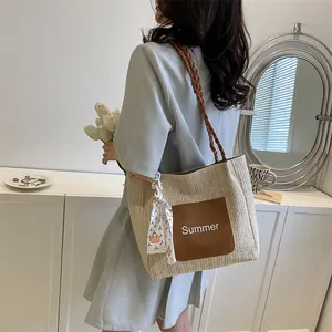 Chic cream woven straw tote bag with brown leather pocket and decorative scarf detail