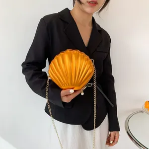 Chic orange shell-shaped crossbody bag with gold chain and pearl zipper detail