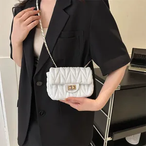 Close-up of white quilted leather texture with gold metal buckle and chain strap