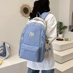 Dettaglio dello zaino oxford blu e beige con toppa rotonda a sorriso e tasche con zip