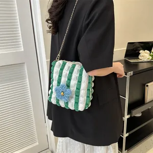 Detailed shot of green and white bubble textured bag with a blue flower and gold chain