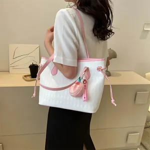 Sac fourre-tout blanc matelassé avec garniture rose et breloque pêche porté par le mannequin
