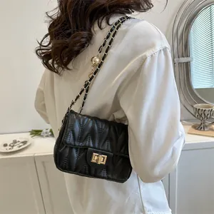 Detailed view of black quilted leather shoulder bag with gold sphere buckle and chain