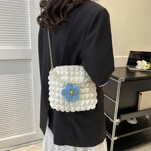 Detailed view of white bubble texture crossbody bag with pearl chain and floral charm