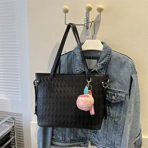 Détail du cabas matelassé noir avec breloque pêche et boucle en métal sur denim