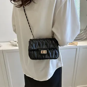 Detail of black quilted leather shoulder bag with gold chain strap and metal turn-lock