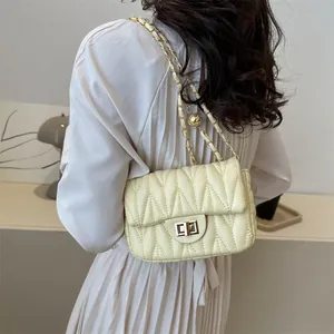 Detail of yellow quilted chain bag with gold sphere ornament and metal lock