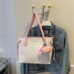Détail du sac cabas blanc matelassé avec anses roses et breloque pêche sur denim