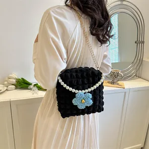 Detail of black bubble texture shoulder bag with gold chain and white pearl handle strap