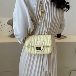 Detail of light yellow chevron matelassé crossbody bag with gold chain strap
