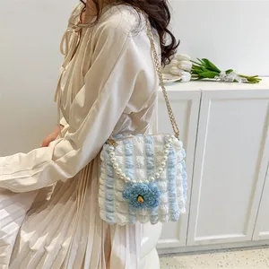 Close-up of blue and white striped puff bag with pearl handle and plush flower detail