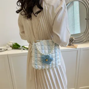 Detailed view of striped bubble bag featuring pearl handle and plush flower charm