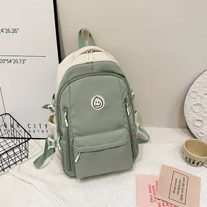 Dettaglio dello zaino Oxford verde salvia e beige con patch sorriso e doppie tasche frontali
