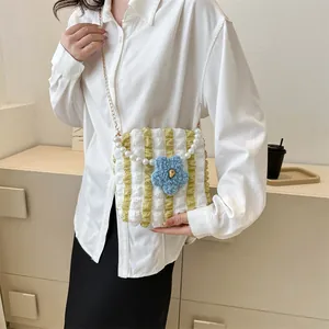 Detail of a ruffled bubble bag featuring a blue floral charm and elegant pearl handle