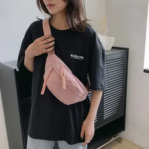 Detail van lichtroze nylon crossbodytas met getextureerde stof en gevlochten ritstrekker