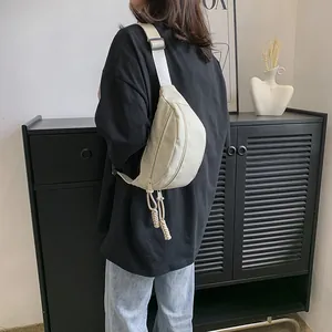 Detail van beige nylon crossbodytas met stijlvolle gevlochten ritslabels op een model