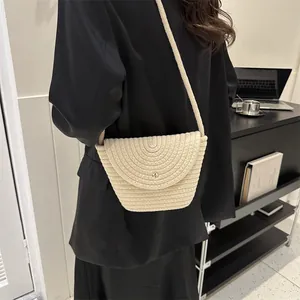 Detail of hand-woven beige shoulder bag with golden cylinder clasp on black blazer