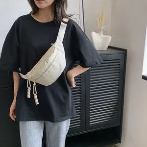 Detail van een beige nylon heuptas met gevlochten ritsen gedragen door een model in zwart