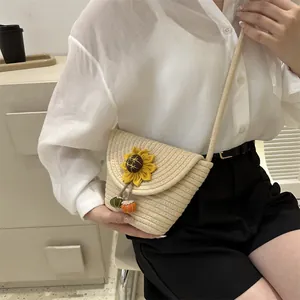 Detail of beige woven straw bucket bag featuring a vibrant yellow sunflower floral accent