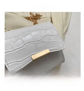 Close-up of white crocodile pattern leather texture with golden rectangular metal clasp