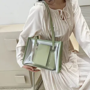 Detail of light green PVC tote bag with matching inner pouch on model wearing a beige dress
