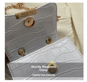 Detail of sturdy magnetic gold closure and white crocodile pattern on leather bag
