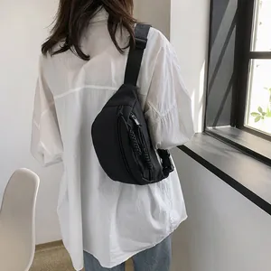 Detail van een zwarte nylon crossbody borsttas met dubbele ritsen en gevlochten koorden