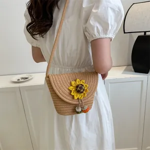 Detail of woven straw bucket bag with a yellow sunflower ornament and colorful charm tassels