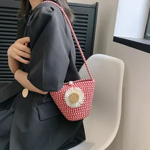 Détail du sac seau en paille rouge avec fleur de marguerite et fermoir perle