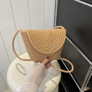 Detail showing the woven texture and golden button closure of the khaki straw bag
