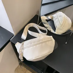 Detailweergave van de witte nylon borsttas met een getextureerde touw rits trekker