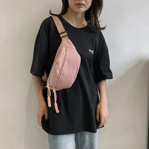 Minimalistische roze nylon borsttas met verstelbare riem gedragen door een model