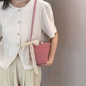 Détail du sac seau tissé rouge avec nœud en dentelle et perle décorative