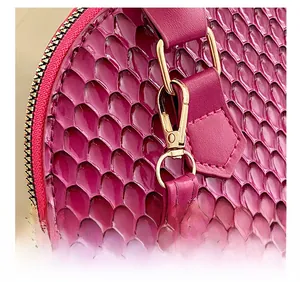 Détail macro du sac magenta avec texture peau de serpent et ferrures métalliques dorées