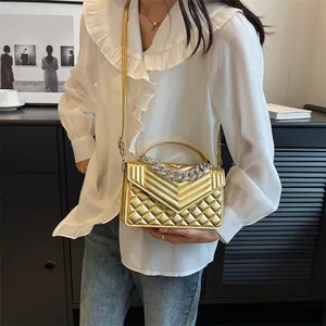 Détail du sac à bandoulière doré avec matelassage chevron et chaîne en métal argenté