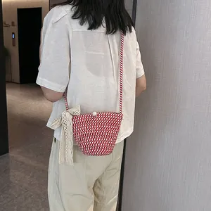 Détail du sac seau tissé rouge et blanc avec fermoir perle et nœud en dentelle délicat