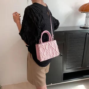 Detail of pink quilted handbag showing raw edge texture, handles and shoulder strap