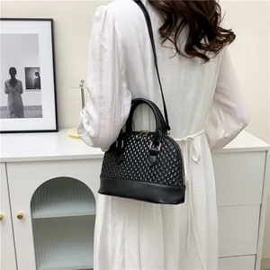 Sac à main noir avec texture à écailles et détails dorés porté en bandoulière pour femme
