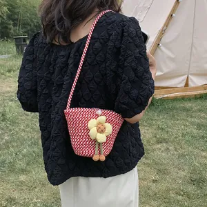 Detail of red and white woven bucket bag featuring a 3D yellow flower and pearl detail