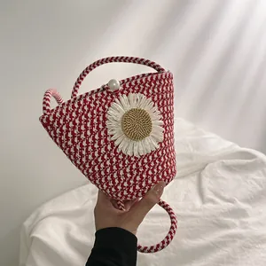 Gros plan sur un sac seau en paille à carreaux rouges avec fleur marguerite et bouton perle