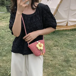 Detailed view of hand-woven red and white checkered mini bucket bag with yellow flower
